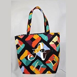 May include: A black tote bag with colorful geometric patterns and the name "Amara" in white lettering.