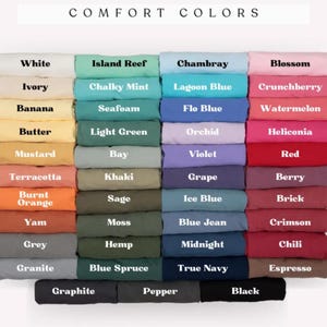 May include: A colour chart showcasing a range of fabric colours, including white, blue, pink, and green. The text "COMFORT COLORS" is at the top. Each colour is labelled with its name, such as "White," "Island Reef," and "Chambray."