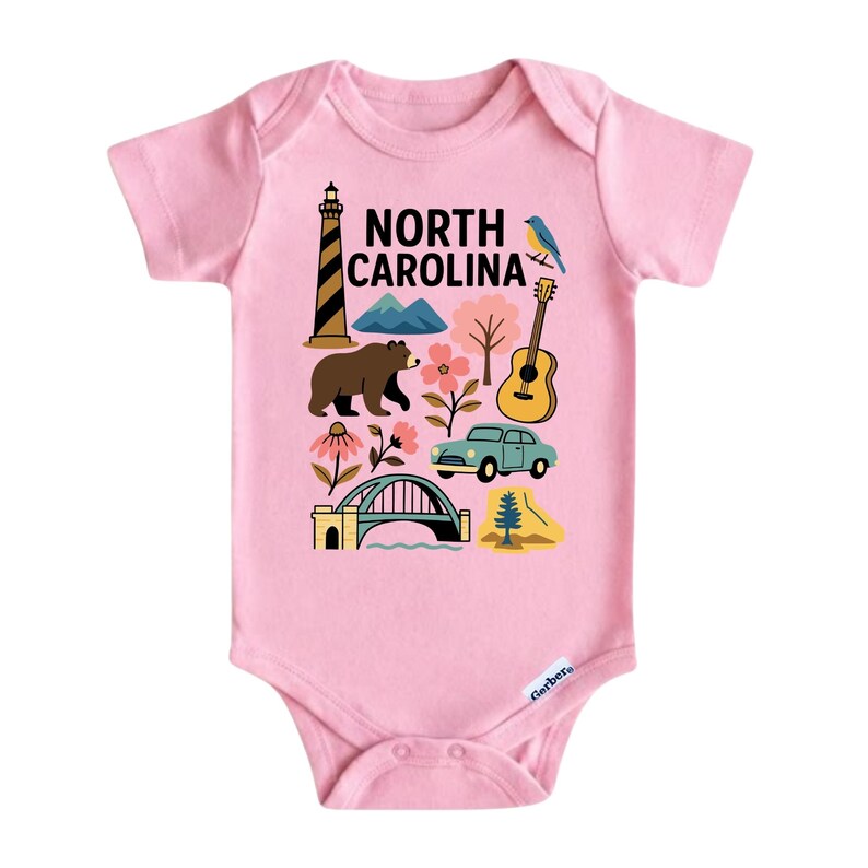 May include: Pink baby bodysuit with a colorful graphic featuring North Carolina landmarks and symbols. The design includes a lighthouse, mountains, a bear, a guitar, a car, and the text "NORTH CAROLINA".