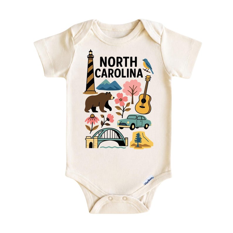 May include: Cream-colored baby bodysuit with a colorful graphic of North Carolina landmarks, including a lighthouse, mountains, bear, flowers, guitar, car, bridge, and a bird. The text "NORTH CAROLINA" is printed in black. Made of soft material.