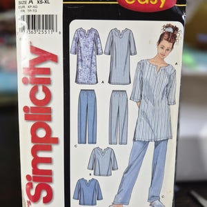 Puede incluir: Un sobre de patrón de costura Simplicity, número 7050, para un conjunto de túnica y pantalón. La portada presenta ilustraciones de una túnica con escote de muesca y mangas tres cuartos, junto con pantalones rectos. Texto: 'IT'S SO easy' y 'Simplicity'.