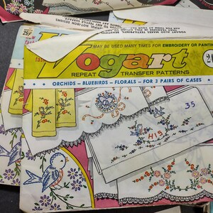 May include: A vintage Vogart transfer pattern booklet for embroidery or painting. The cover features a pink background with white linens and floral designs. The text on the cover reads "Vogart Repeat Transfer Patterns Orchids - Bluebirds - Florals - For 3 Pairs of Cases".