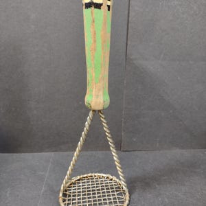 May include: Vintage potato masher with a wooden handle painted green and tan, accented with black stripes. The masher features a wire mesh base and a twisted wire support. A kitchen utensil for mashing potatoes or other soft foods.