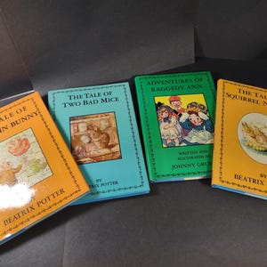 May include: A collection of four vintage children's books. The titles are "The Tale of Benjamin Bunny," "The Tale of Two Bad Mice," "Adventures of Raggedy Ann," and "The Tale of Squirrel Nutkin." The books are by Beatrix Potter and Johnny Gruelle.