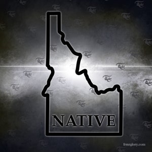 May include: A black outline of the state of Idaho with the word "NATIVE" printed below it. The background is a dark gray with a white light shining through the center. The image is textured and has a vintage look.