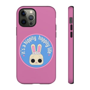 May include: Pink phone case with a blue circle and a cartoon bunny wearing a flower crown. The circle has the text "it's a hippity hoppity life" around it.