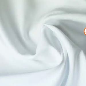 May include: White fabric with a smooth, soft texture. The fabric is folded and draped, showing its flowing nature.