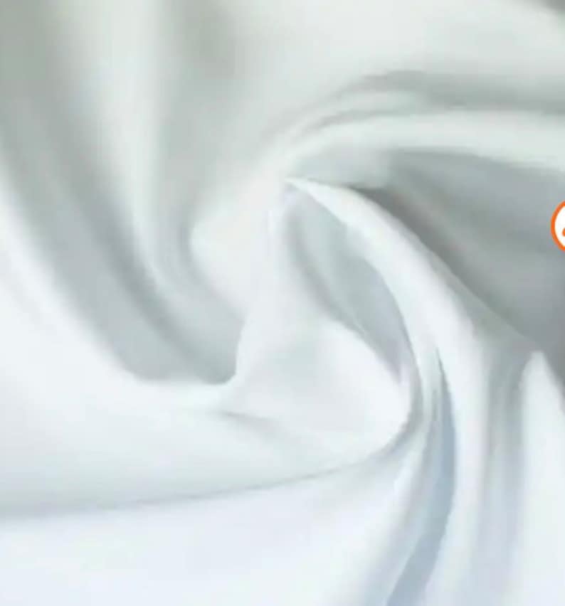 May include: White fabric with a smooth, soft texture. The fabric is folded and draped, showing its flowing nature.
