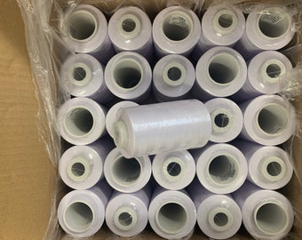 May include: A cardboard box containing many white thread spools. The spools are cylindrical with a central hole. One spool is wrapped in clear plastic and is positioned on top of the others.