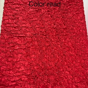 May include: A vibrant red fabric with a textured, ruffled design. The fabric has a shiny, satin-like appearance and features the text "Color read". The overall effect is a rich, decorative textile.