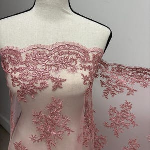 K&ouml;nnte beinhalten: Staubrosa Spitzenstoff mit floraler und Blattstickerei. Die zarte Spitze wird auf einer Schaufensterpuppe pr&auml;sentiert, die die komplizierten Details und die Textur zeigt. Ideal f&uuml;r Brautmode, Kleider oder andere besondere Anl&auml;sse.