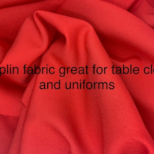May include: A close-up shot of a bright red poplin fabric, suitable for table cloths and uniforms. The fabric has a smooth texture and a subtle sheen. The text "Poplin fabric great for table cloth and uniforms" is visible.