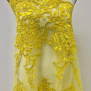 May include: Yellow floral lace fabric with sequins. The lace has a delicate floral pattern with a sheer background.