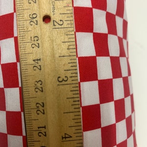 May include: Red and white checkered fabric with a wooden ruler measuring 2 inches. "Made in China" is printed on the ruler.