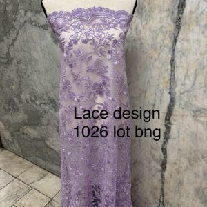 Może przedstawiać: Lawendowa koronka prezentowana na manekinie. Tkanina ma szczegółowy kwiatowy wzór i falisty brzeg. Na tkaninie widoczny jest napis "Lace design 1026 lot bng".