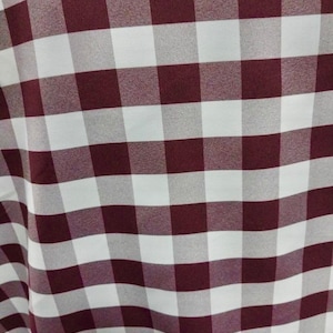 May include: A close-up of a burgundy and white checkered fabric. The fabric has a subtle sheen and a soft texture.