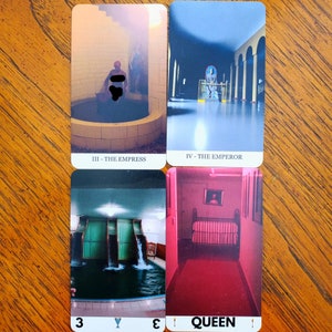 Four cards from the liminal space tarot deck on a wooden table. On the top left is the Empress, top right is the Emperor, bottom left is the Three of Cups, and bottom right is the Queen of Wands.