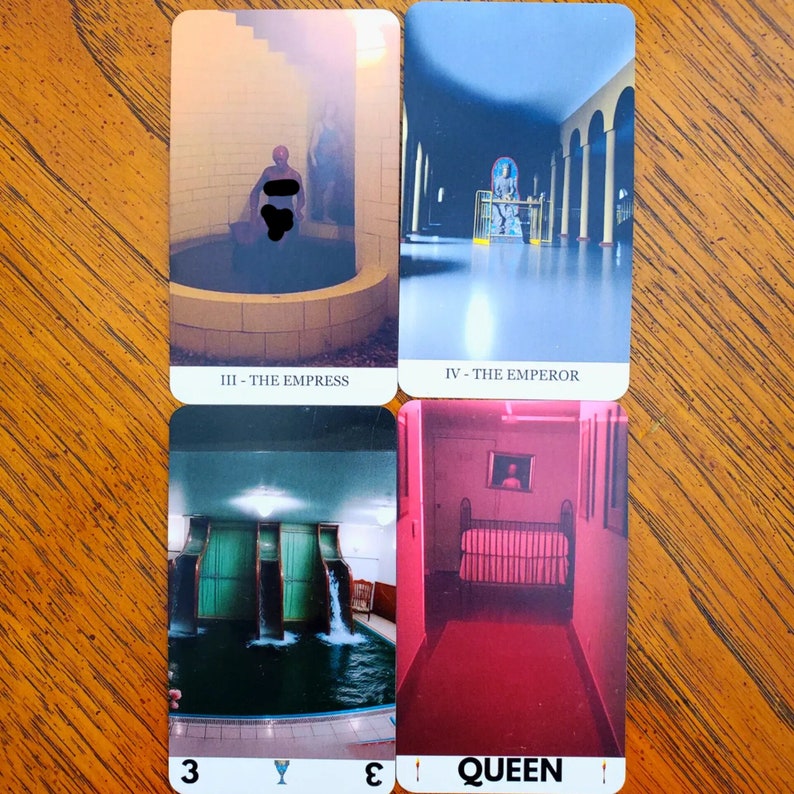 Four cards from the liminal space tarot deck on a wooden table. On the top left is the Empress, top right is the Emperor, bottom left is the Three of Cups, and bottom right is the Queen of Wands.