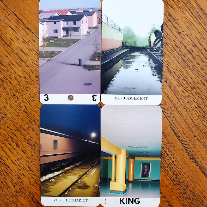 Four more cards from the liminal space tarot deck on a wooden table. On the top left is the Three of Pentacles, top right is Judgement, bottom left is The Chariot, and bottom right is the King of Wands.