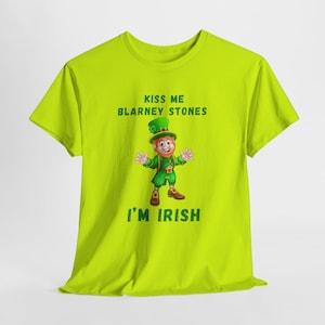 May include: A lime green t-shirt with a cartoon leprechaun wearing a green hat and holding a pot of gold. The text "Kiss Me Blarney Stones I'm Irish" is printed on the shirt.