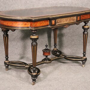 May include: An antique, half-moon table with a black top and intricate wood detailing. The table features black legs with gold accents and decorative carvings. The table's dimensions are approximately 48 inches long, 24 inches wide, and 30 inches high.