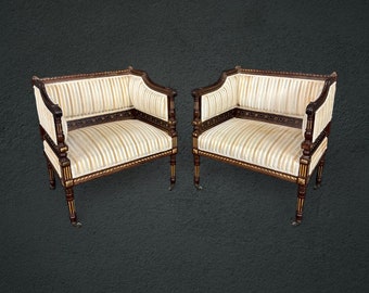 May include: A pair of antique chairs with a striped fabric upholstery and dark wood frames. The chairs have ornate details and are on casters.