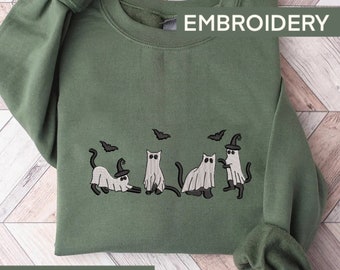 May include: A military green sweatshirt with an embroidered design of five cats dressed as ghosts. The cats are wearing witch hats and have bats flying around them. The text "EMBROIDERY" is printed in white at the top of the sweatshirt.