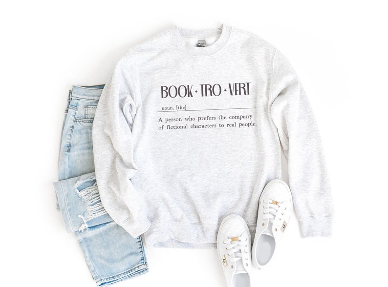 May include: A gray sweatshirt with the text "BOOK-TRO-VERT" and a definition: "A person who prefers the company of fictional characters to real people."