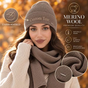 Könnte beinhalten: Eine taupefarbene Strickmütze mit Umschlag, die den gestickten Text Custom Text aufweist. Die Mütze hat ein kleines rechteckiges Metallschild an der Seite. Das Set enthält einen passenden taupefarbenen Strickschal mit gerippter Textur.