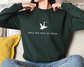 May include: A dark green sweatshirt with a white goose graphic and the text "peace was never an option".