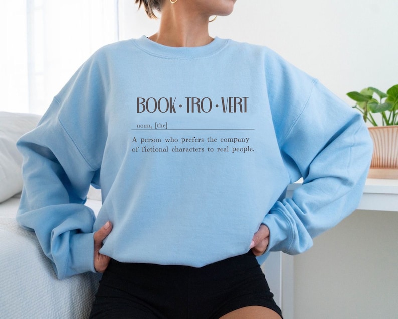 May include: Light blue sweatshirt with the text "BOOK-TRO-VERT" and the definition: "A person who prefers the company of fictional characters to real people."