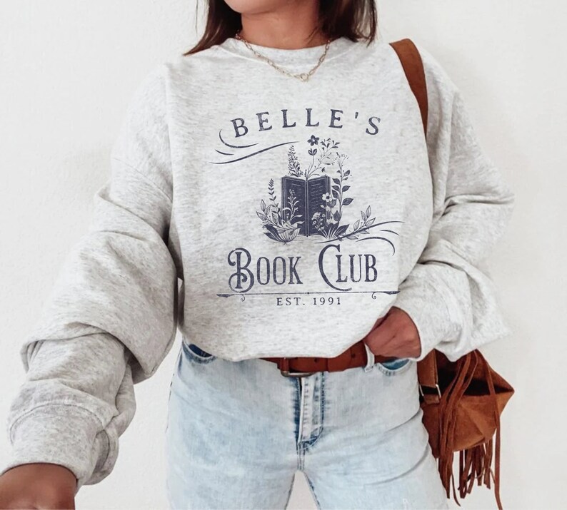 May include: A grey sweatshirt with the text "Belle's Book Club Est. 1991" and a graphic of an open book with flowers.