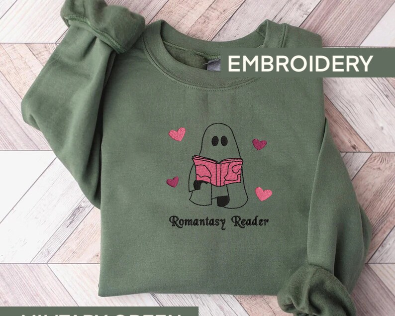 May include: Green sweatshirt with an embroidered design of a ghost reading a book with the text "Romantasy Reader" and pink hearts.