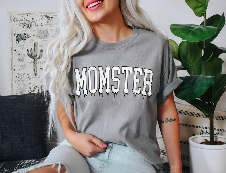 May include: A gray t-shirt with the word "MOMSTER" printed in white with a dripping effect.