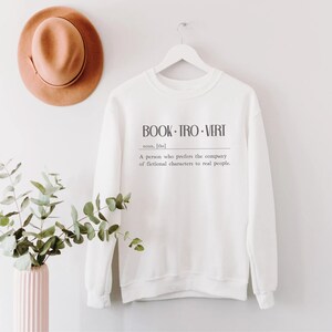 May include: White sweatshirt with the text "BOOK-TRO-VERT" and the definition: "A person who prefers the company of fictional characters to real people."