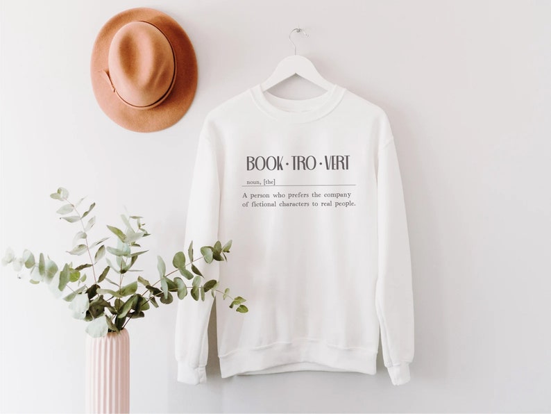 May include: White sweatshirt with the text "BOOK-TRO-VERT" and the definition: "A person who prefers the company of fictional characters to real people."