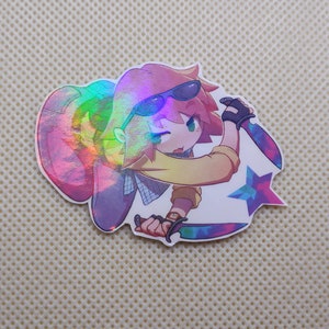 May include: A holographic sticker featuring a cartoon character wearing sunglasses and a yellow shirt, holding two knives. The character is standing in front of a blue and purple star.
