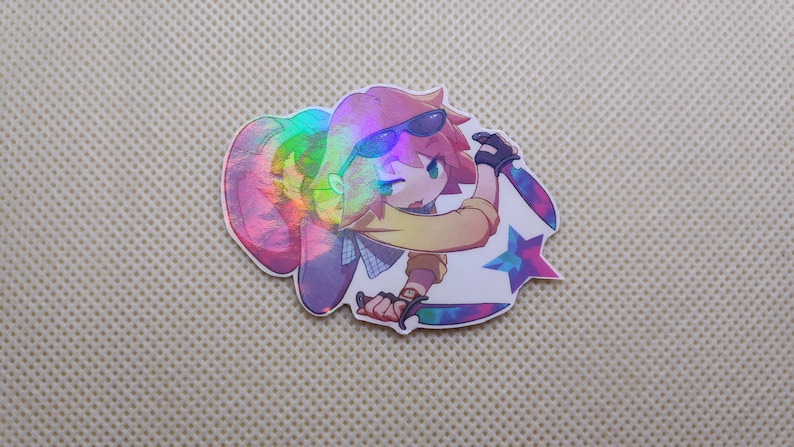 May include: A holographic sticker featuring a cartoon character wearing sunglasses and a yellow shirt, holding two knives. The character is standing in front of a blue and purple star.