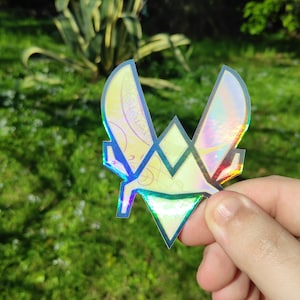 May include: A holographic sticker with a geometric design in shades of yellow, green, blue, and purple. The sticker features a stylized letter "W" in the center.