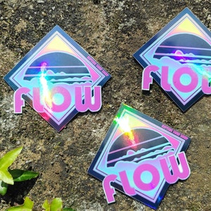 May include: Three iridescent holographic stickers with a black and pink design. The stickers feature a sunset scene with the word "FLOW" in pink letters.