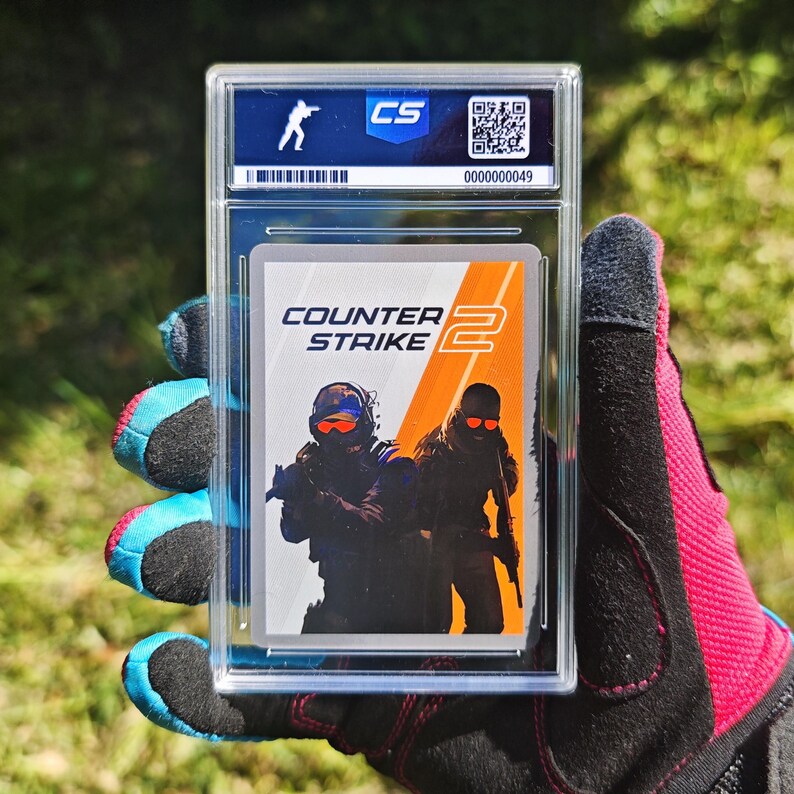 Pu&ograve; includere: Una carta collezionabile valutata con il logo e i personaggi del gioco "Counter-Strike 2". La carta &egrave; racchiusa in un supporto di plastica trasparente con un logo "CS" e un numero di serie. Lo sfondo &egrave; verde sfocato.