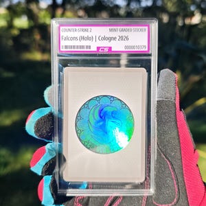 Puede incluir: Una pegatina Counter-Strike 2 Falcons (Holo) Cologne 2026 con calificación mint, encapsulada en una funda protectora de plástico transparente. La pegatina circular muestra un emblema de halcón holográfico azul y verde con patrones.