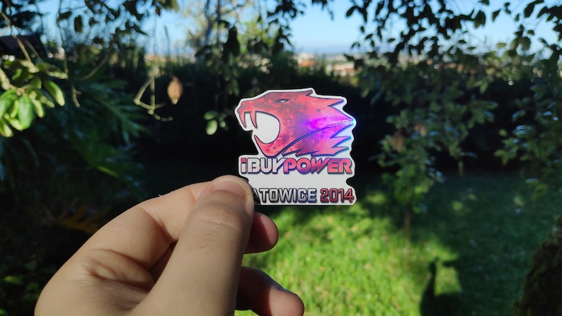May include: A red and black sticker with a holographic finish featuring a snarling red and black creature with the text "iBUYPOWER" and "KATOWICE 2014" below.