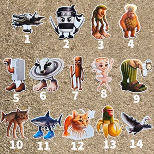 Op de afbeelding: Een verzameling grillige stickerontwerpen met verschillende karakters en objecten. Bevat een ninja-koffiekopje, een haai met sneakers, een ballerina, een kat en andere eigenzinnige illustraties. De stickers zijn gerangschikt op een getextureerd, lichtbruin oppervlak.
