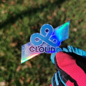 May include: A holographic sticker featuring the Cloud9 esports logo in blue with the text "CLOUD9" underneath.