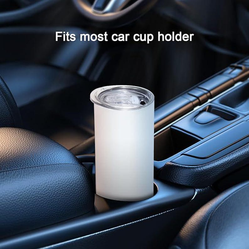 May include: White travel mug with a lid, sitting in a car cup holder. The text "Fits most car cup holder" is displayed above the mug.