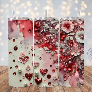 May include: Three stainless steel tumblers with a white background and red, pink, and white floral designs. The tumblers have a clear lid and a straw. The tumblers are decorated with hearts, glitter, and pearls. The tumblers are labeled "R&M Creations Hand Made Crafts".