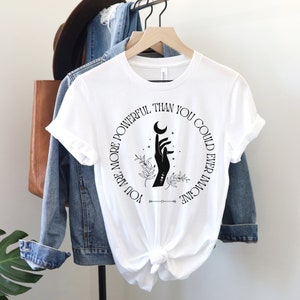 May include: White t-shirt with a black circle graphic featuring a hand holding a crescent moon and the text "You are more powerful than you could ever imagine".
