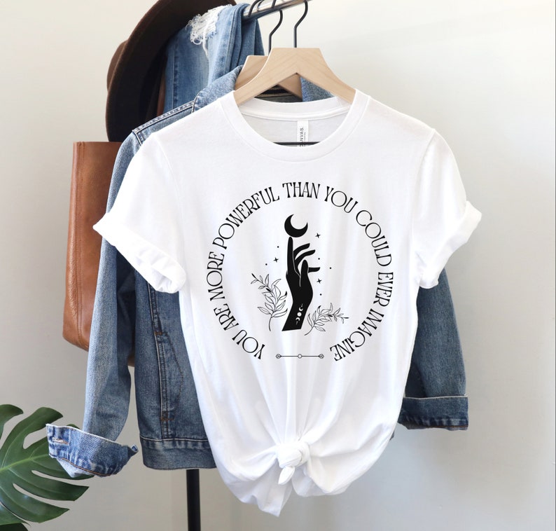 May include: White t-shirt with a black circle graphic featuring a hand holding a crescent moon and the text "You are more powerful than you could ever imagine".