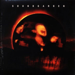 May include: Soundgarden album cover featuring the band's name in white block letters at the top. The image shows blurred figures in a dark circle against a black background with a red glow.